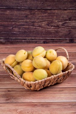 Ahşap arka planda kayısılar. Sepette bir yığın taze kayısı. Kapat.