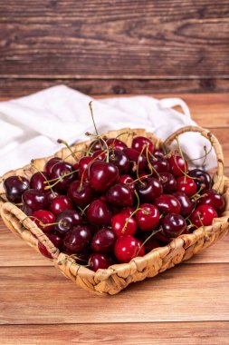 Taze kiraz. Tahta arka planda sepetin içinde olgun kirazlar. Toplu kiraz. Kapat.