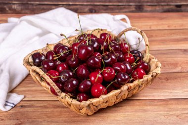 Taze kiraz. Tahta arka planda sepetin içinde olgun kirazlar. Toplu kiraz. Kapat.