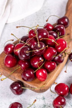 Taze kiraz. Taş bir arka planda, tahta servis tabağında olgun kirazlar. Toplu kiraz. Kapat.