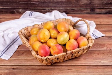 Taze kayısılar. Ahşap arka planda sepetin içinde olgun kayısılar. Toplu kayısılar. Kapat.