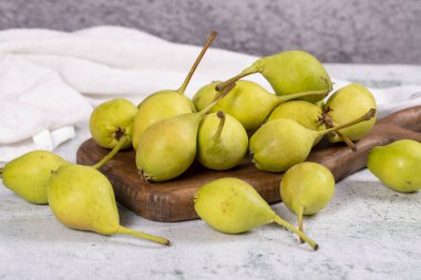 Taze armut. Taş bir arka planda, ahşap servis tabağında olgun armutlar. Toplu armut. Kapat.