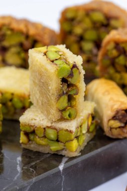 Fıstıklı baklava çeşitleri. Beyaz arka planda izole edilmiş baklava çeşitliliği. Geleneksel Türk mutfağı lezzetleri. Ortasında şam fıstığı şurubu olan tatlılar. Kapat.