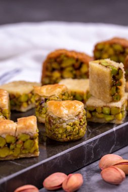 Fıstıklı baklava çeşitleri. Karanlık bir arka planda baklava çeşitleri. Geleneksel Türk mutfağı lezzetleri. Ortasında şam fıstığı şurubu olan tatlılar. Kapat.