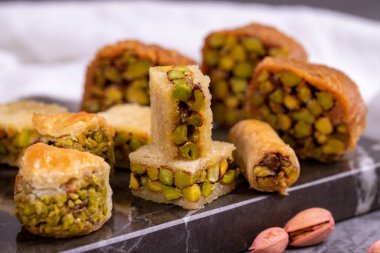 Fıstıklı baklava çeşitleri. Karanlık bir arka planda baklava çeşitleri. Geleneksel Türk mutfağı lezzetleri. Ortasında şam fıstığı şurubu olan tatlılar. Kapat.