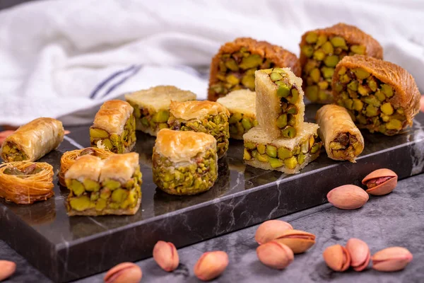 Fıstıklı baklava çeşitleri. Karanlık bir arka planda baklava çeşitleri. Geleneksel Türk mutfağı lezzetleri. Ortasında şam fıstığı şurubu olan tatlılar. Kapat.