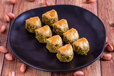 Fıstıklı baklava. Ahşap zeminde fıstıkla dolu bir baklava. Türk mutfağı tatlısı. Kapat.