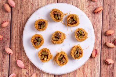 Bulbul Kadayif ve Pistachio. Ahşap zeminde şam fıstıklı Kadayif baklavası. Türk mutfağı tatlısı. Yakın plan. yerel adı Antep Fstkl Bulbul Kadayf