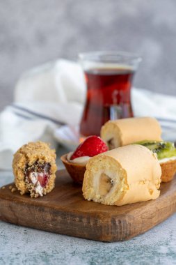 Lezzetli atıştırmalıklar. Yuvarlak pasta, çikolatalı pasta ve arka planda meyveli tart. Kapat.