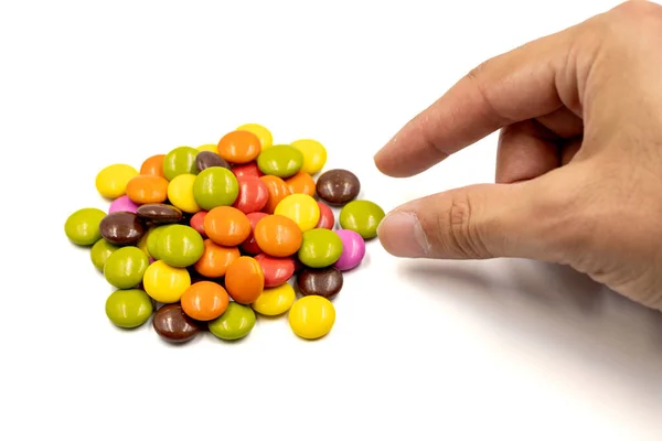 Adult hand reaching for candies or bonbon. Colorful candies and adult hand on a white background