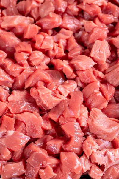 Cubed meat. Chopped red meat on stone background. Butcher products. Close up