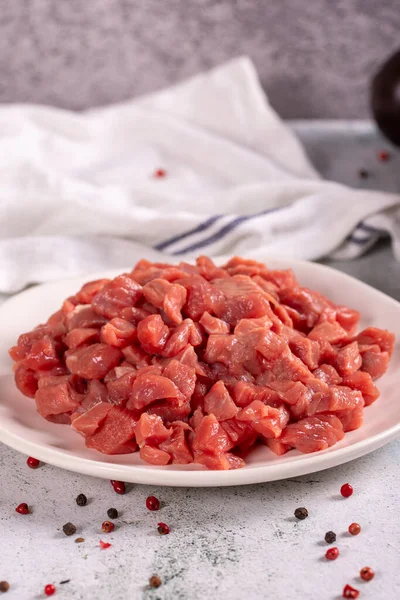 Cubed meat. Red meat in a chopped plate on a stone floor. Butcher products. close up