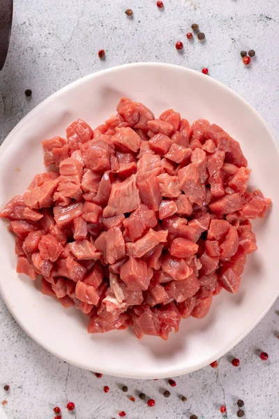 Cubed meat. Red meat in a chopped plate on a stone floor. Butcher products. close up. Top view