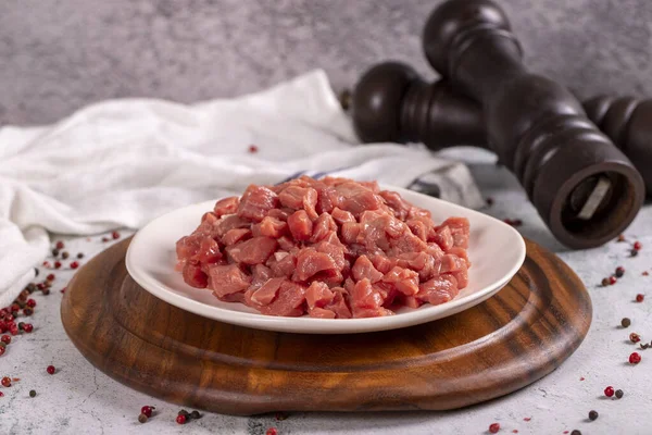 Cubed meat. Red meat in a chopped plate on a stone floor. Butcher products. close up