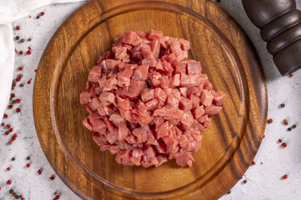 Cubed meat. Chopped red meat in a wooden serving dish on a stone background. Butcher products. close up