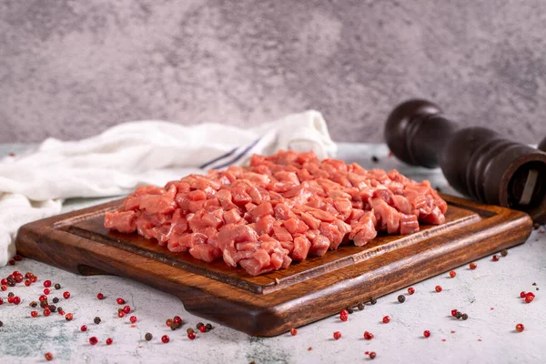 Cubed meat. Chopped red meat in a wooden serving dish on a stone background. Butcher products. close up