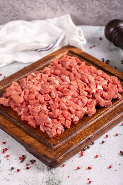 Cubed meat. Chopped red meat in a wooden serving dish on a stone background. Butcher products. close up