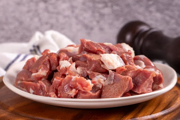 Lamb cubed meat. Chopped red meat in a plate on a stone floor. Butcher products. close up