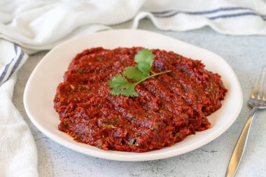 Adjika veya acı biber ezmesi. Acı kırmızı biber harissa sosu. Arkaplanda baharatlı aperatif var. Kapat.