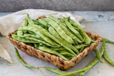 Ripe green beans. Fresh and raw green beans in basket on stone background. Organic food. close up