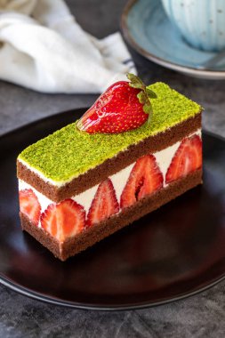 Pistachio and Strawberry Cake. Cake with pistachio and strawberry inside in a plate. On dark background. close up