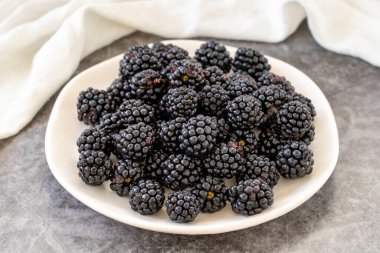 Black mulberry on dark background. Fresh and juicy black mulberry on the plate. Organic food. close up