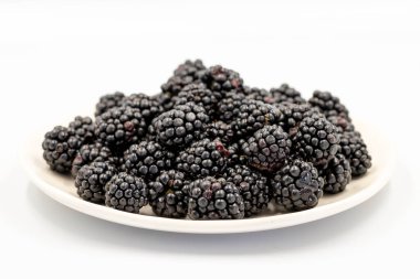 Black mulberry isolated on white background. Fresh and juicy black mulberry on the plate. Organic food. close up