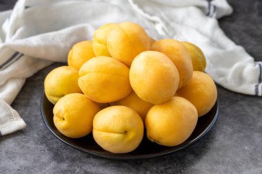 Ripe apricots on a dark background. Fresh and juicy apricots on the plate. Organic food. close up