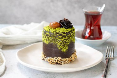 Pistachio and chestnut cake on a gray background. Chocolate covered cake with chestnut and cream inside. close up
