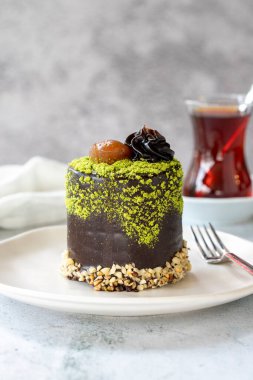 Pistachio and chestnut cake on a gray background. Chocolate covered cake with chestnut and cream inside. close up
