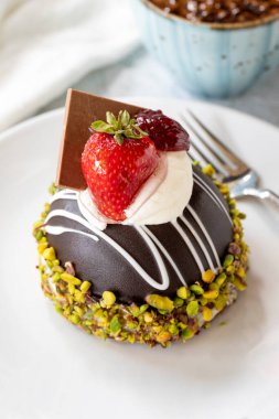 Pistachio and strawberry cake on gray background. Fruit and cream cake covered with chocolate on the outside. close up