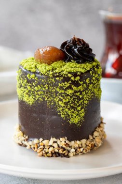Pistachio and chestnut cake on a gray background. Chocolate covered cake with chestnut and cream inside. close up