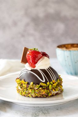 Pistachio and strawberry cake on gray background. Fruit and cream cake covered with chocolate on the outside. close up