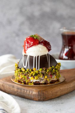 Pistachio and strawberry cake on gray background. Fruit and cream cake covered with chocolate on the outside. close up