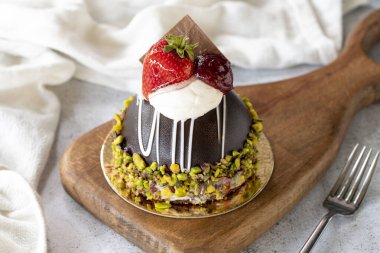 Pistachio and strawberry cake on gray background. Fruit and cream cake covered with chocolate on the outside. close up