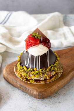 Pistachio and strawberry cake on gray background. Fruit and cream cake covered with chocolate on the outside. close up