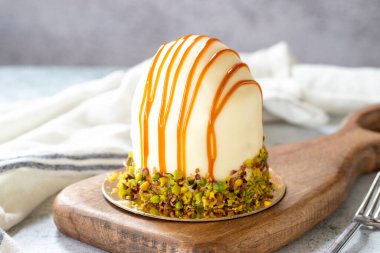 Pistachio and white chocolate cake on a gray background. Fruit and cream cake covered with chocolate on the outside. close up