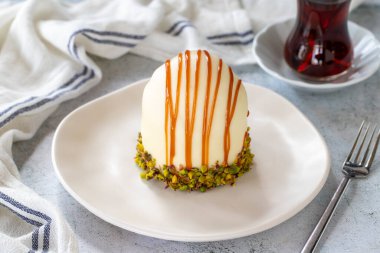 Pistachio and white chocolate cake on a gray background. Fruit and cream cake covered with chocolate on the outside. close up