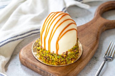 Pistachio and white chocolate cake on a gray background. Fruit and cream cake covered with chocolate on the outside. close up