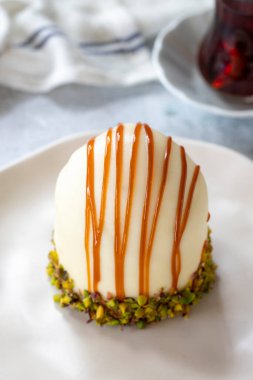 Pistachio and white chocolate cake on a gray background. Fruit and cream cake covered with chocolate on the outside. close up
