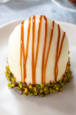 Pistachio and white chocolate cake on a gray background. Fruit and cream cake covered with chocolate on the outside. close up