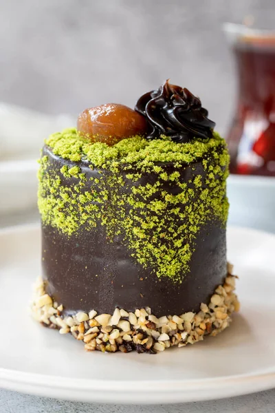 Pistachio and chestnut cake on a gray background. Chocolate covered cake with chestnut and cream inside. close up