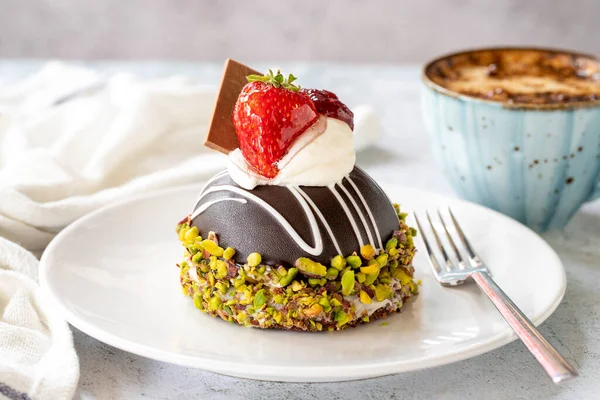 Pistachio and strawberry cake on gray background. Fruit and cream cake covered with chocolate on the outside. close up
