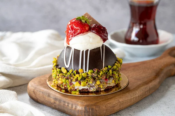 Pistachio and strawberry cake on gray background. Fruit and cream cake covered with chocolate on the outside. close up