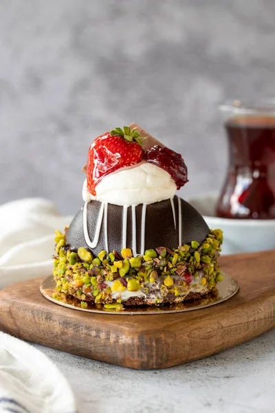 Pistachio and strawberry cake on gray background. Fruit and cream cake covered with chocolate on the outside. close up
