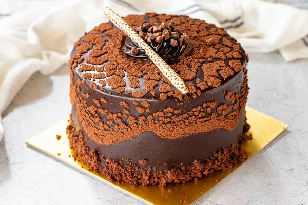 Chocolate chip cake on gray background. Chocolate covered cake with chocolate and cream inside. close up