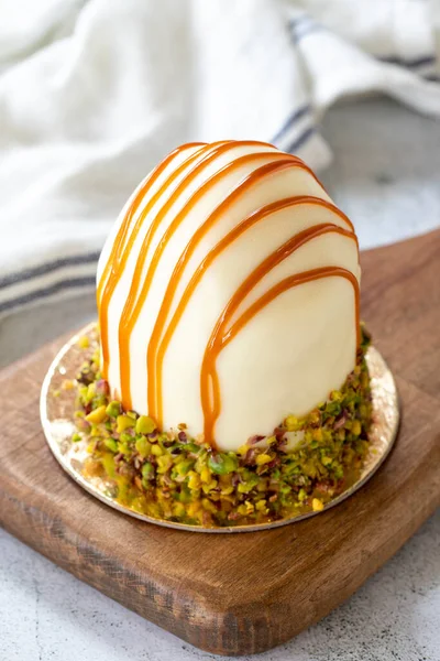 Pistachio and white chocolate cake on a gray background. Fruit and cream cake covered with chocolate on the outside. close up