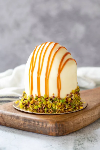 Pistachio and white chocolate cake on a gray background. Fruit and cream cake covered with chocolate on the outside. close up