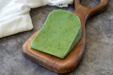 Green gouda cheese. Gouda cheese with basil on a dark background. Dutch cheese. close up