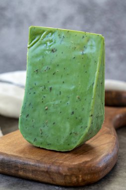 Green gouda cheese. Gouda cheese with basil on a dark background. Dutch cheese. close up